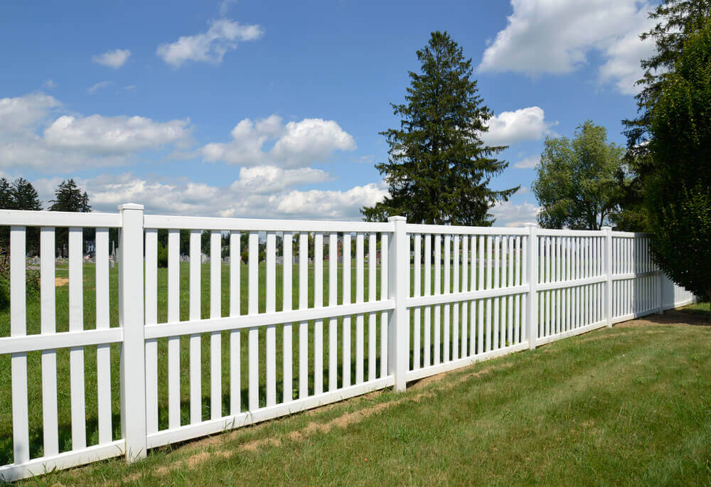 image of a white aluminum fencing panels with nice green grass either side and a tree to the right