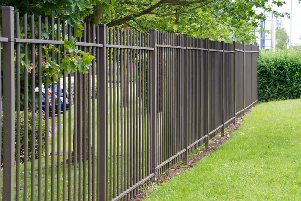 a standard black vertical steel bar fencing panels in a park with green grass everywhere