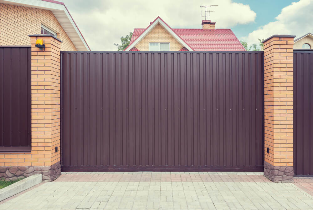image of some dark brown colorbond fencing with some automatic gates at the driveway entrance