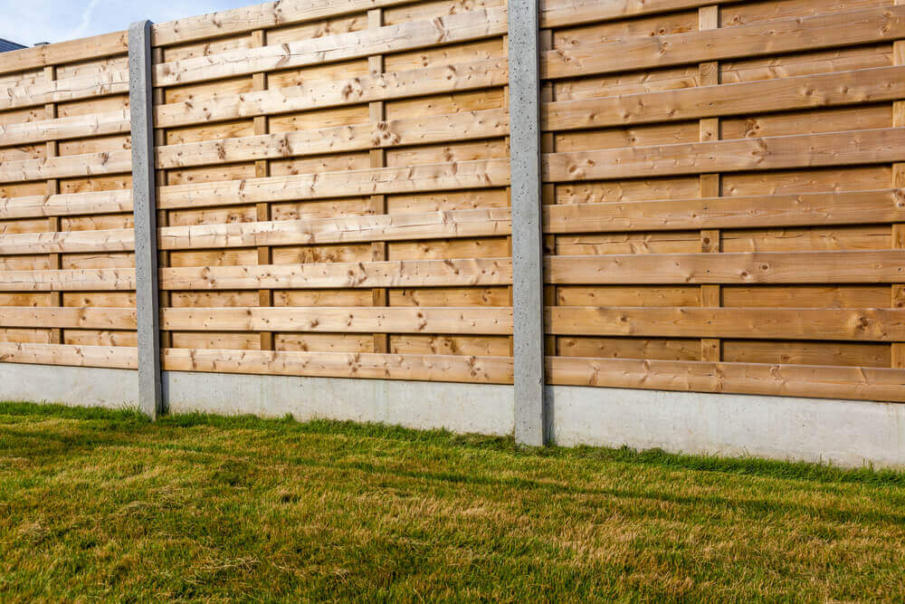 a large fence with horizontal wooden planks and steel vertical supports with a concrete footer made by fencing Ballarat